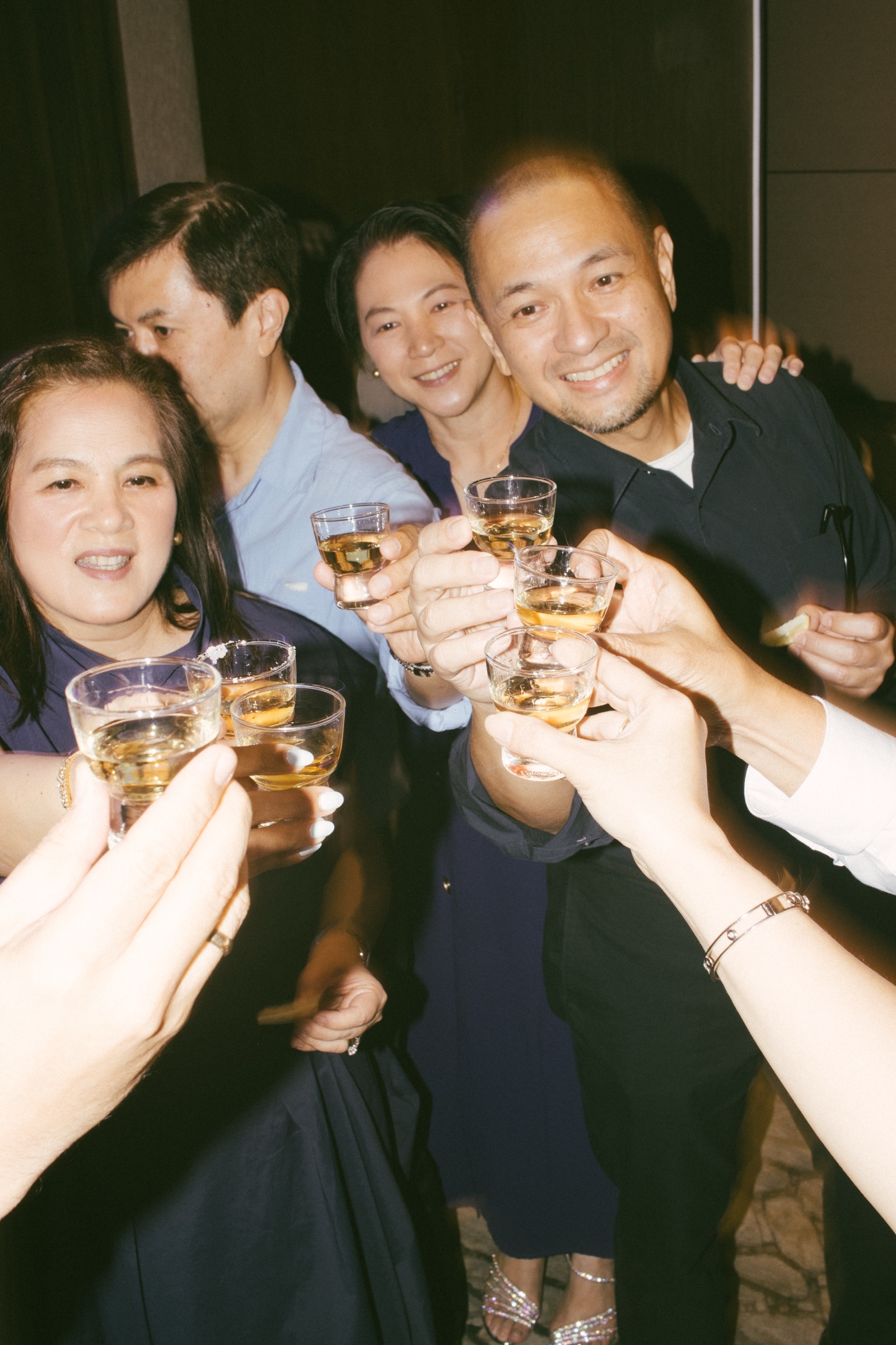 Guests crowd together and raise their glasses for a toast