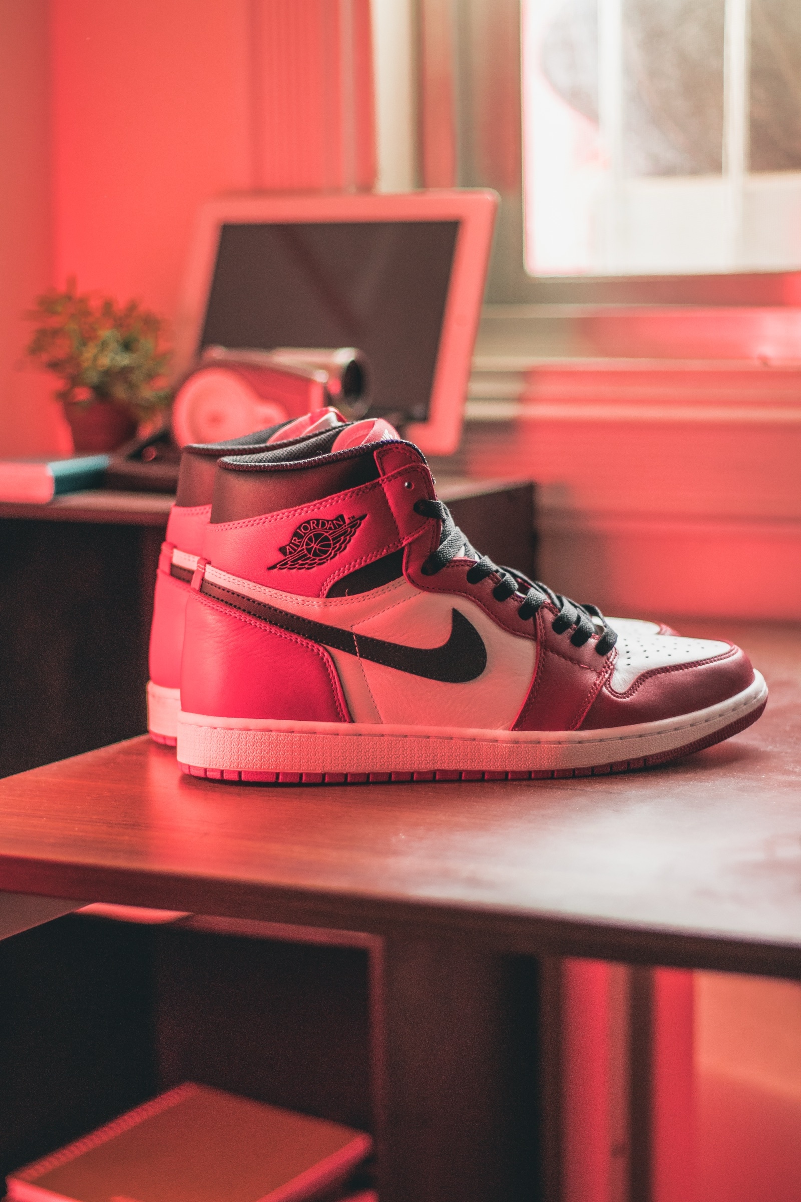 A red and white sneaker on a desk in a room washed with red light